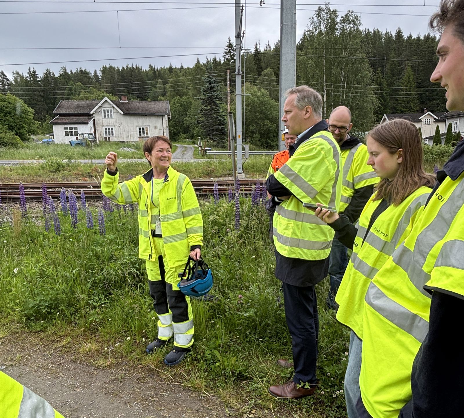 Menn og kvinner i arbeidstøy ved jernbanespor