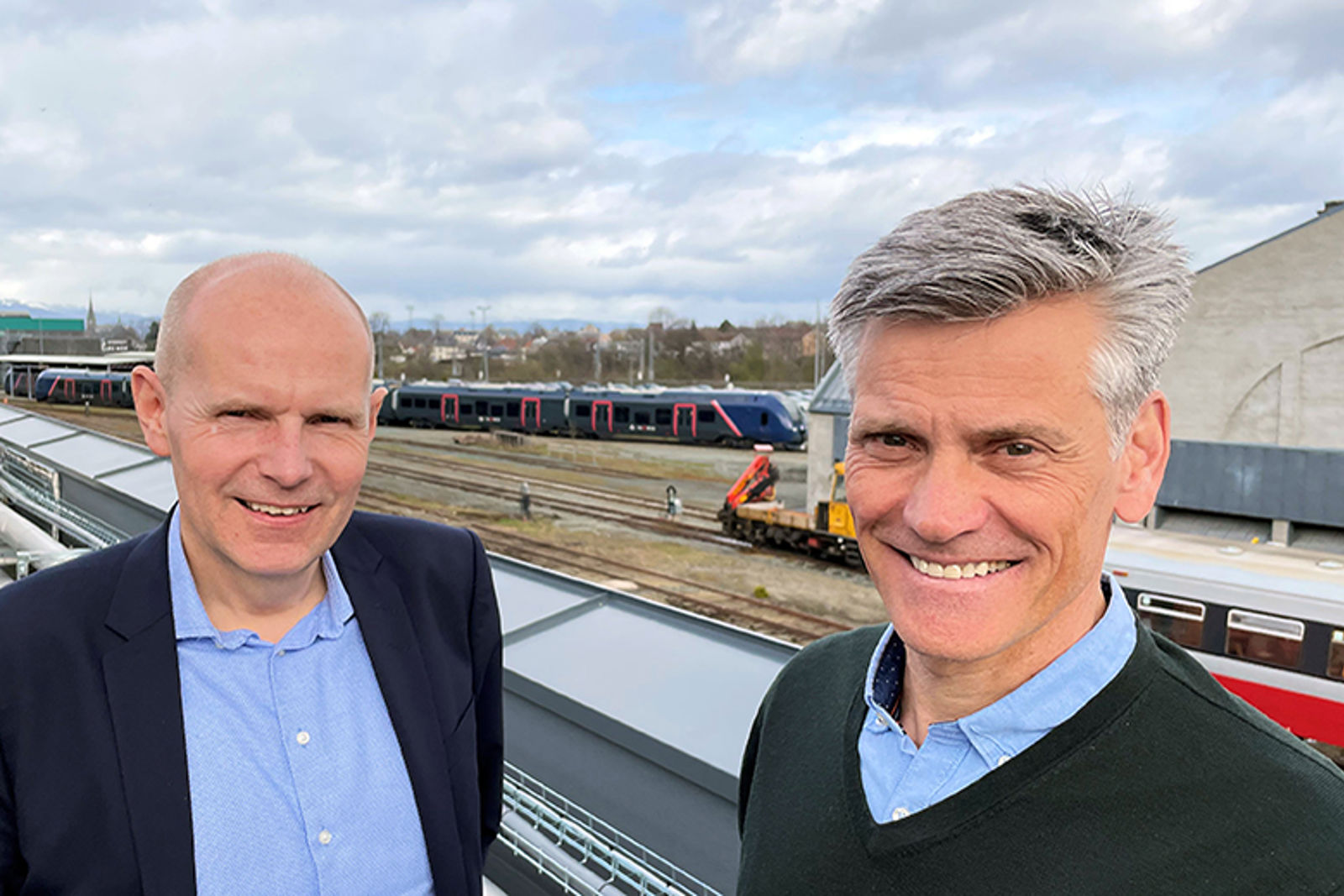 Bilde av to menn foran en togstasjon