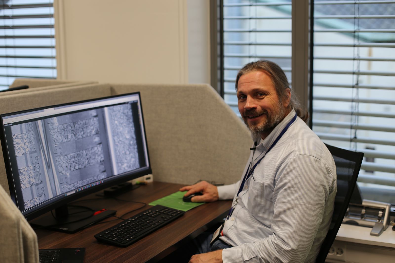 Mann ved PC-skjerm med nærbilde av jernbanespor 