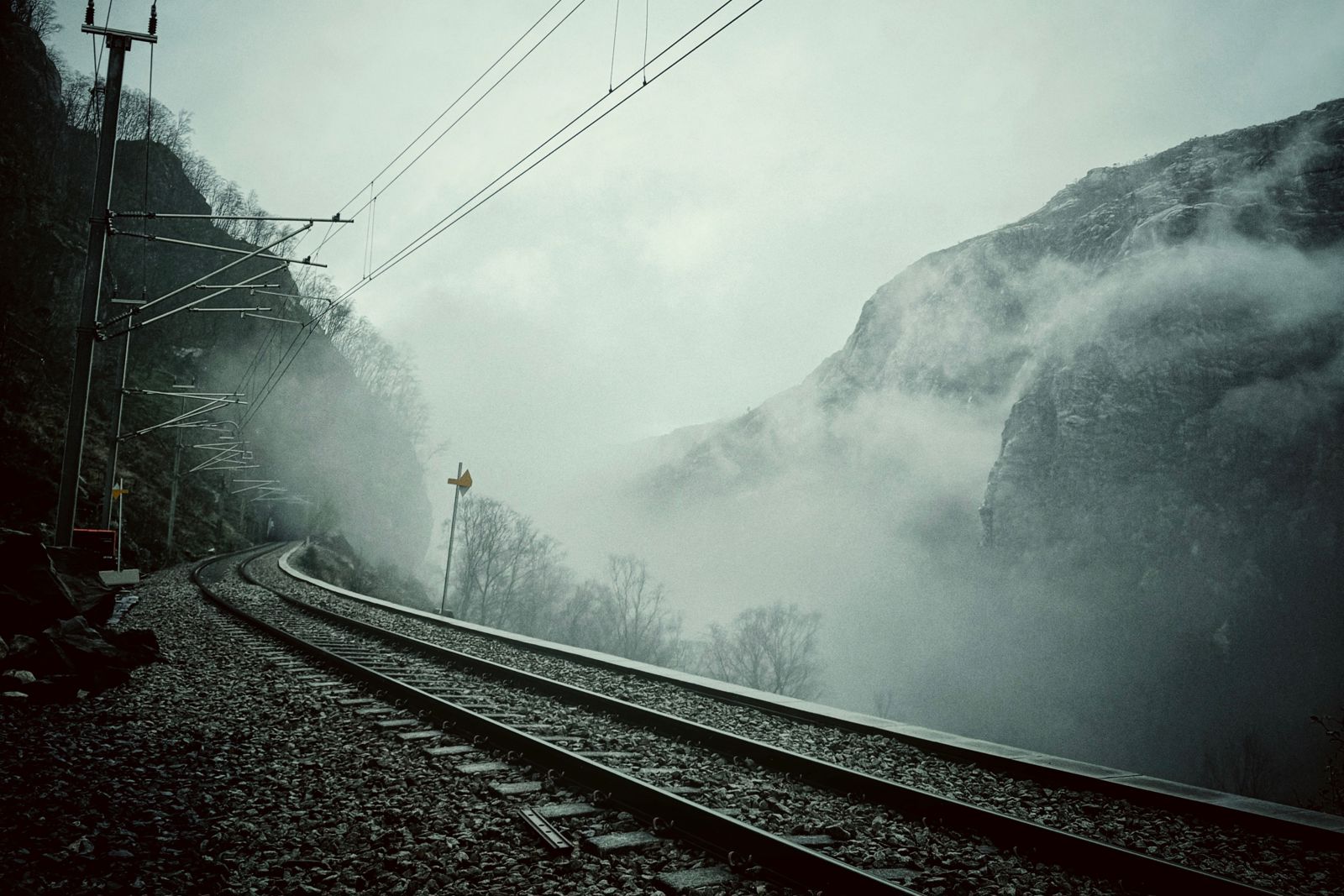 Jernbaneskinner i mørk tåke.