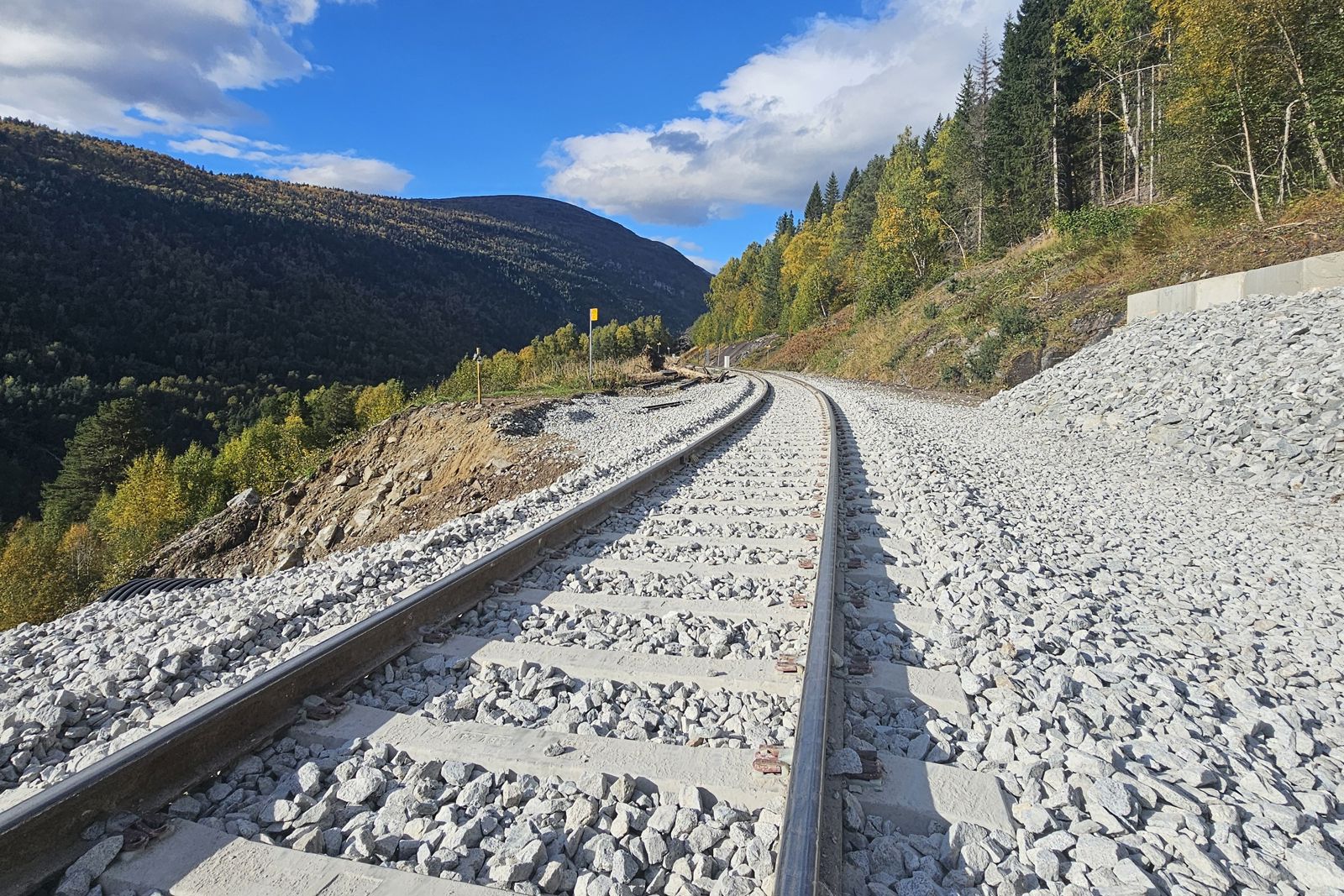 Ferdig lagt spor ved Verma stasjon med fjell i bakgrunnen.